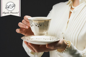 Woman holding ornate gilded tea cup and saucer